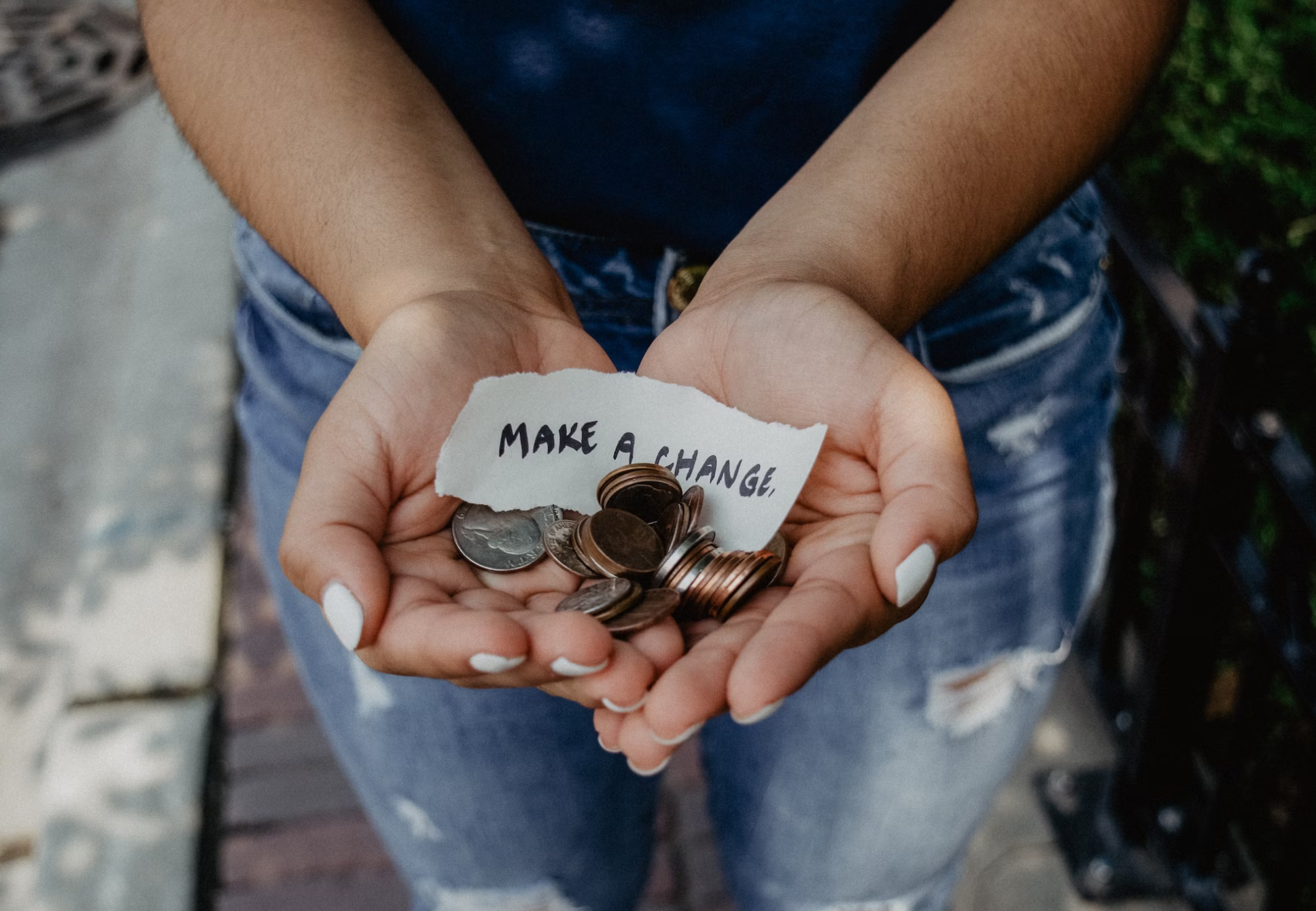 Person holding change in their hands with a note saying "make a change"